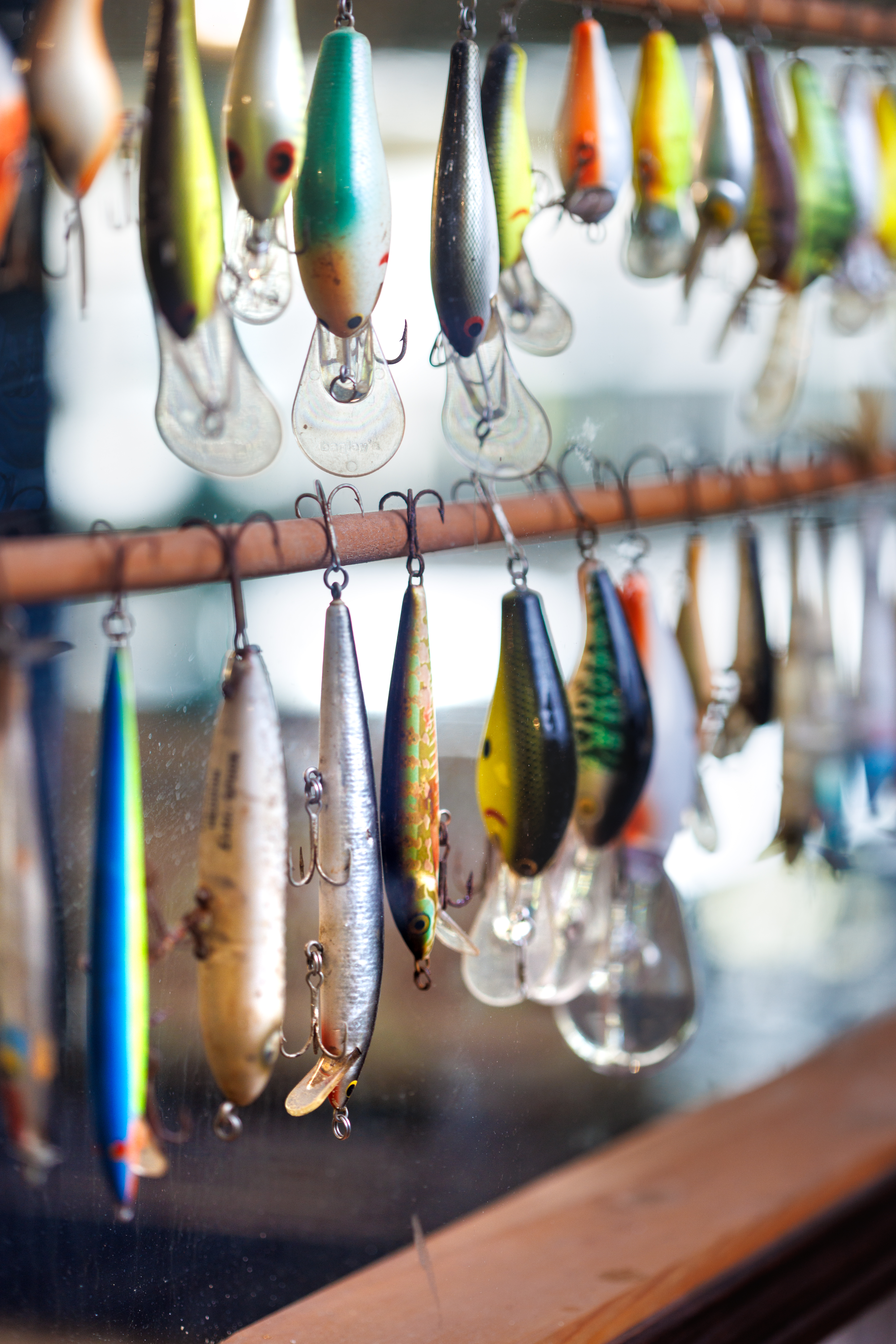 A collection of colorful, vintage fishing lures hanging in rows on a wooden display display rack.