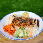 grilled chicken on a bed of white rice, carrots, cucumbers and avocado