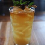yellow drink with mint and cherry garnish