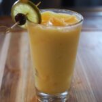 yellow slushy drink with lime and cherry garnish