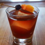 brown drink in a glass with a skewer with a cherry
